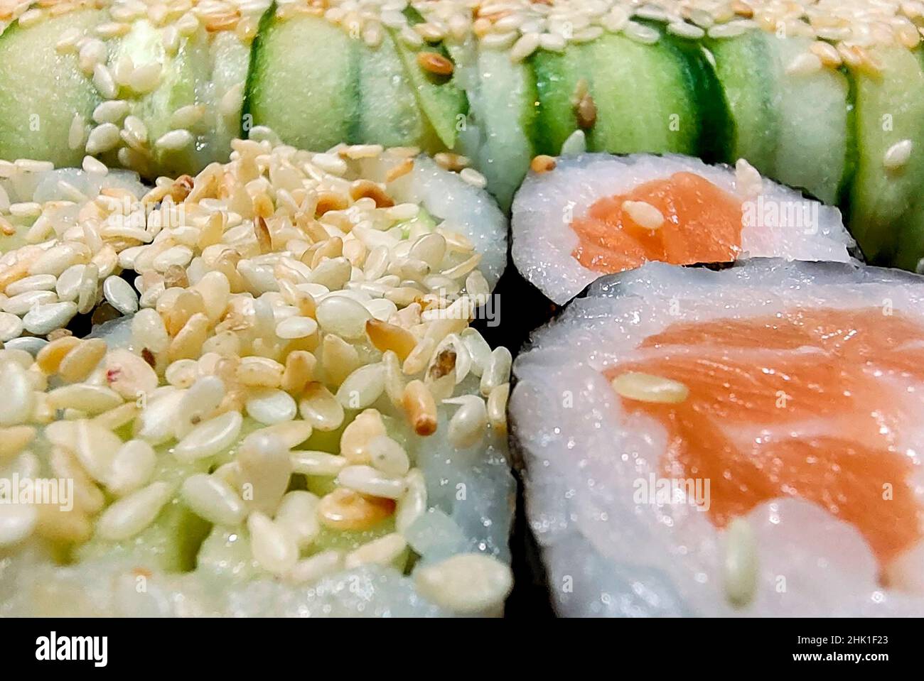 Various sushi rolls are photographed close up. The background is very blurry Stock Photo