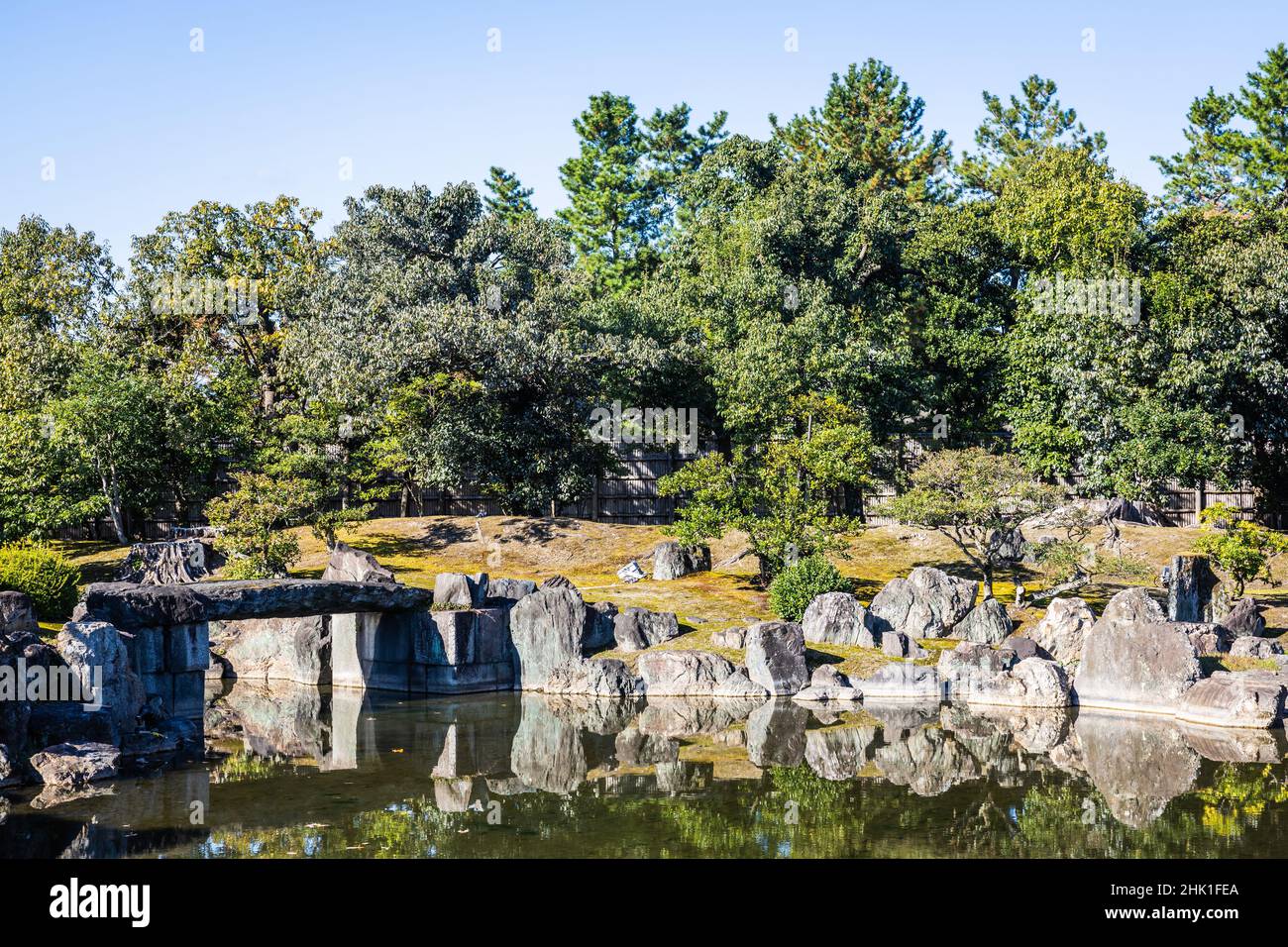 Japanese Garden with a shallow pond and rocks surrounding the edge in daylight. Stock Photo