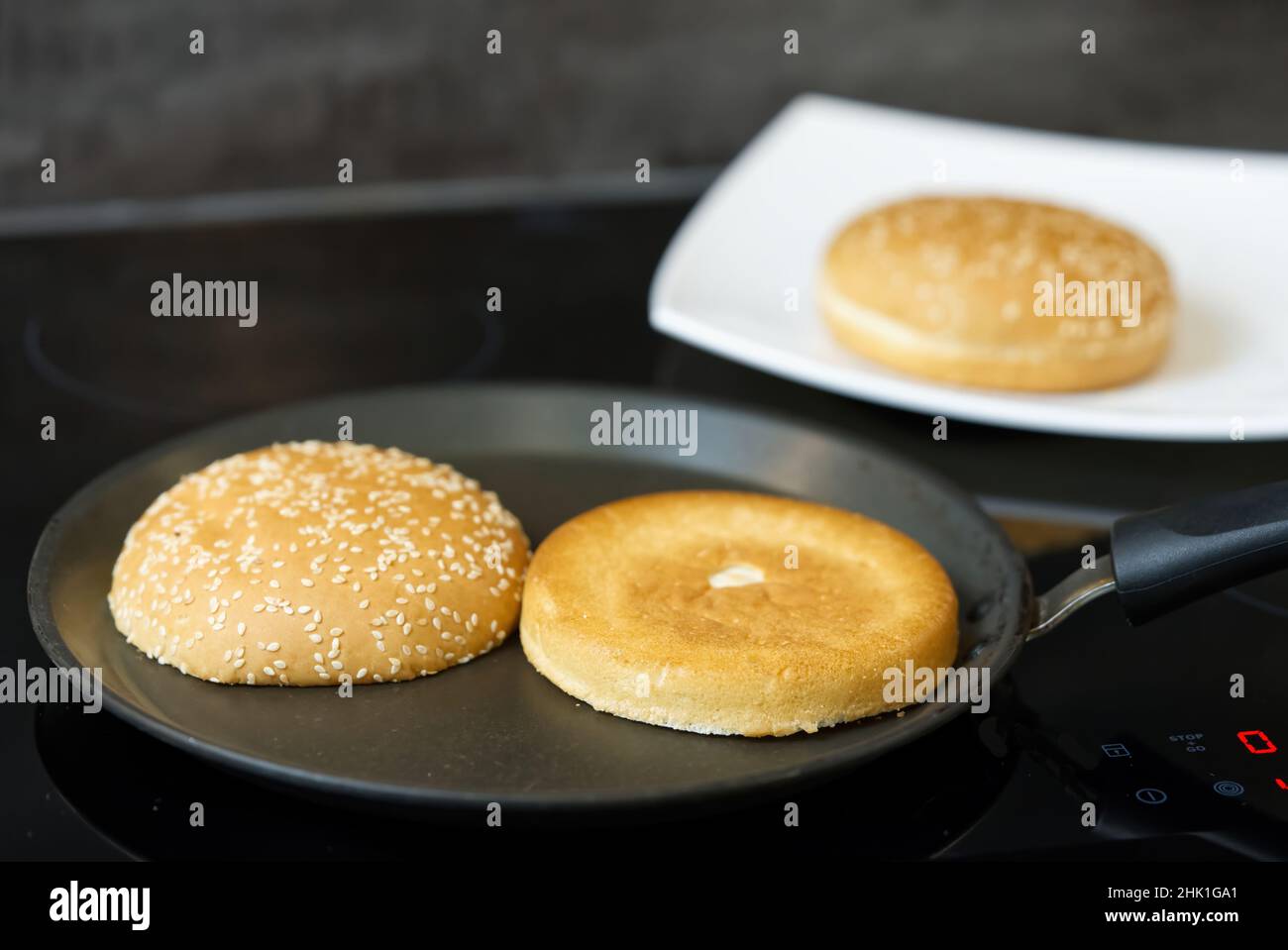 Burger bread with sesame is heating on a grill pan. Process of cooking self  made burgers at home Stock Photo - Alamy