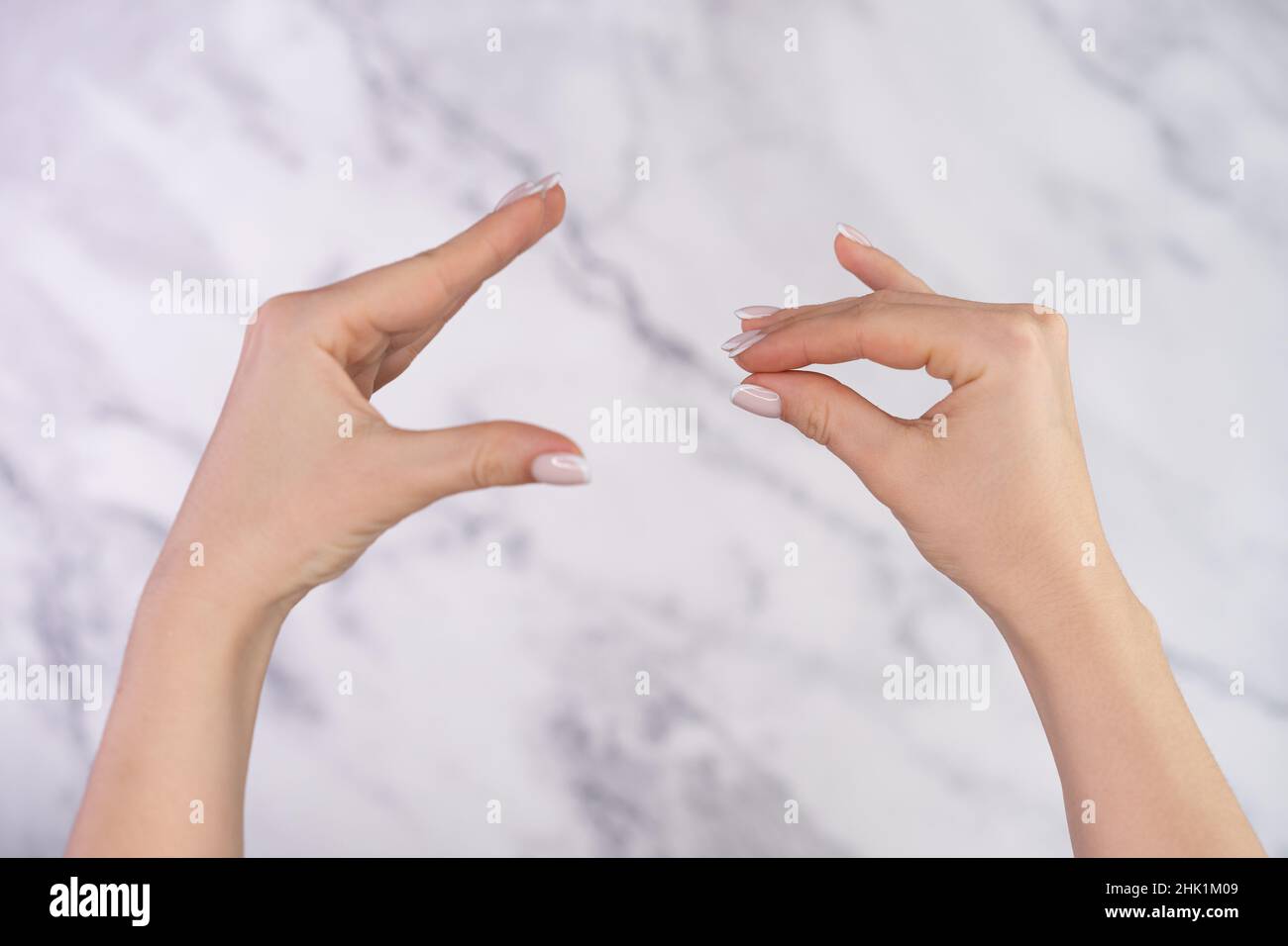 Woman showing bla-bla-bla gesture with hands isolated on marble light background. Empty promises, blah concept. Lier. Stock Photo
