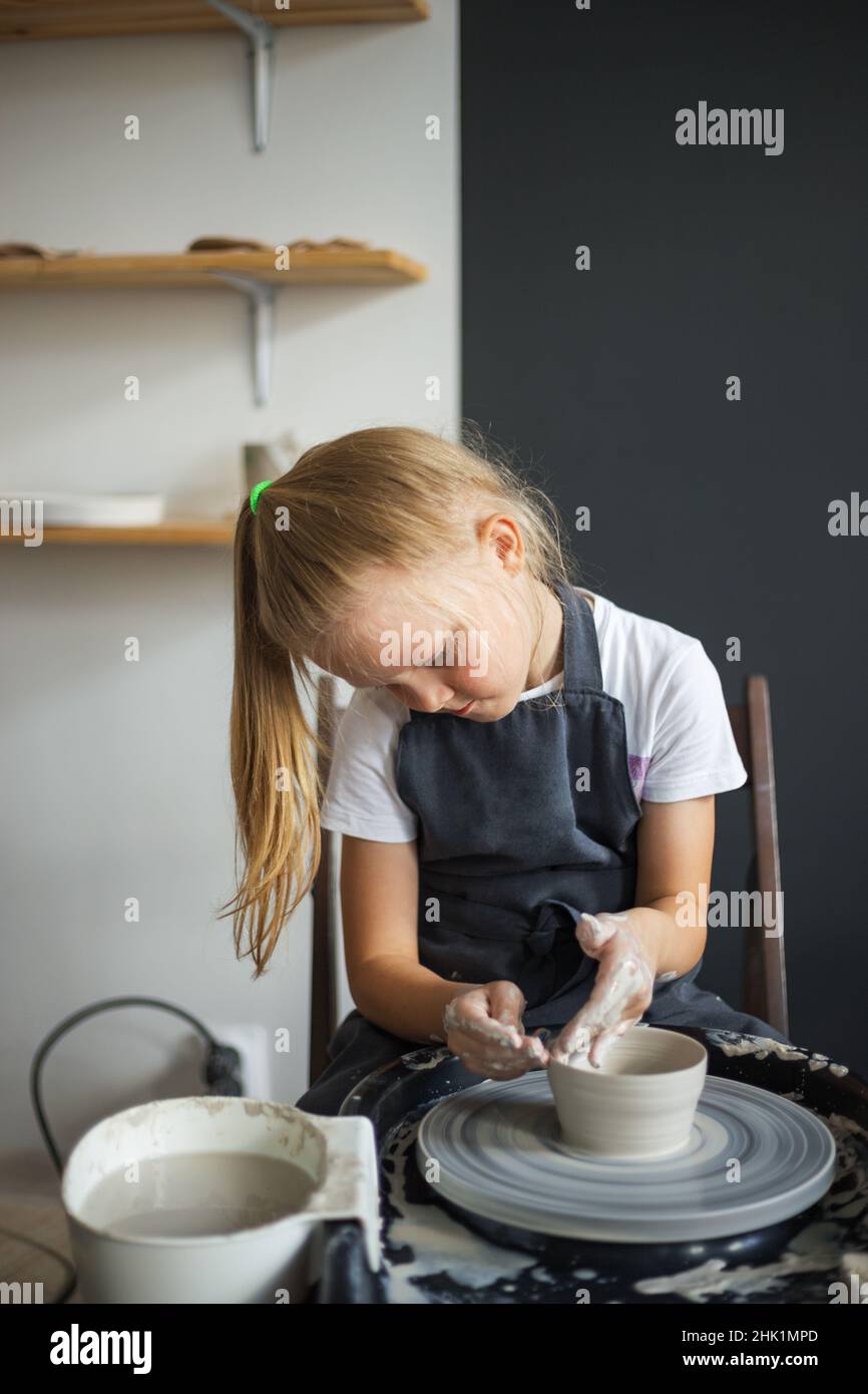 Girl modelling clay on a potter's wheel in the pottery workshop. Stock Photo