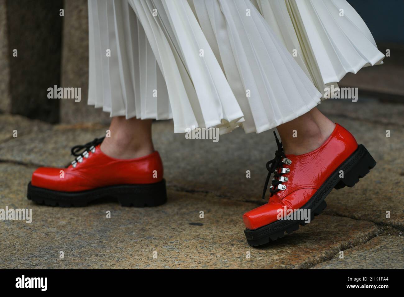 Street style outfit - woman wearing long white dress and red shoes Stock Photo