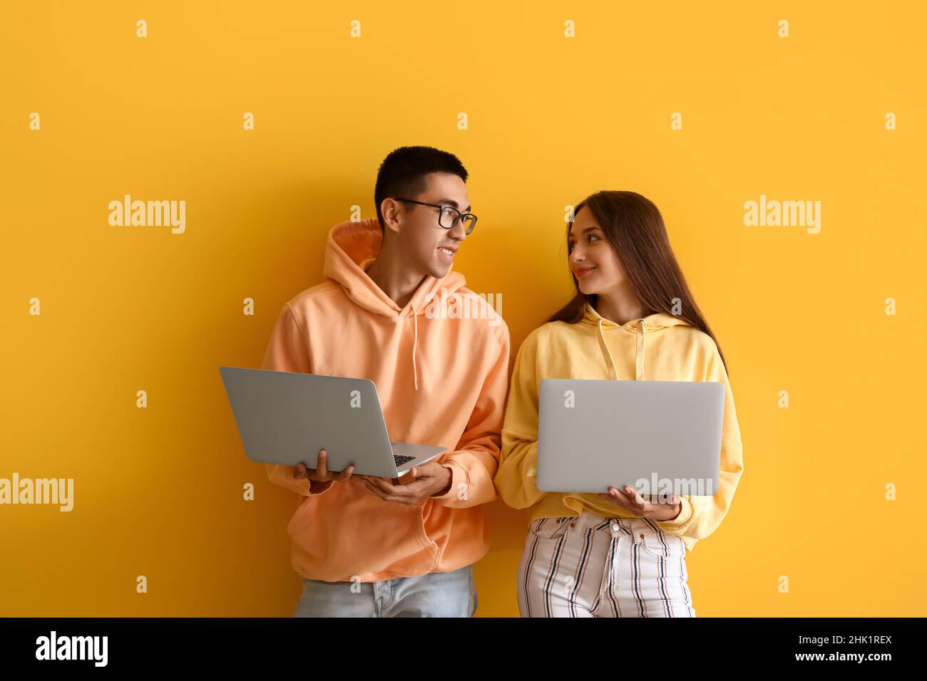 Young couple with laptops on yellow background Stock Photo