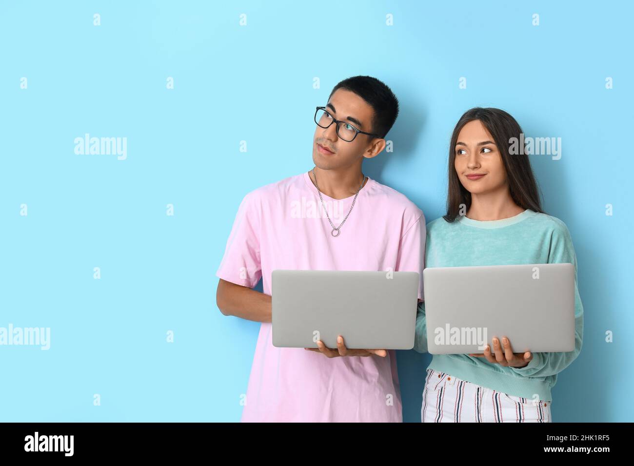 Young couple with laptops on blue background Stock Photo