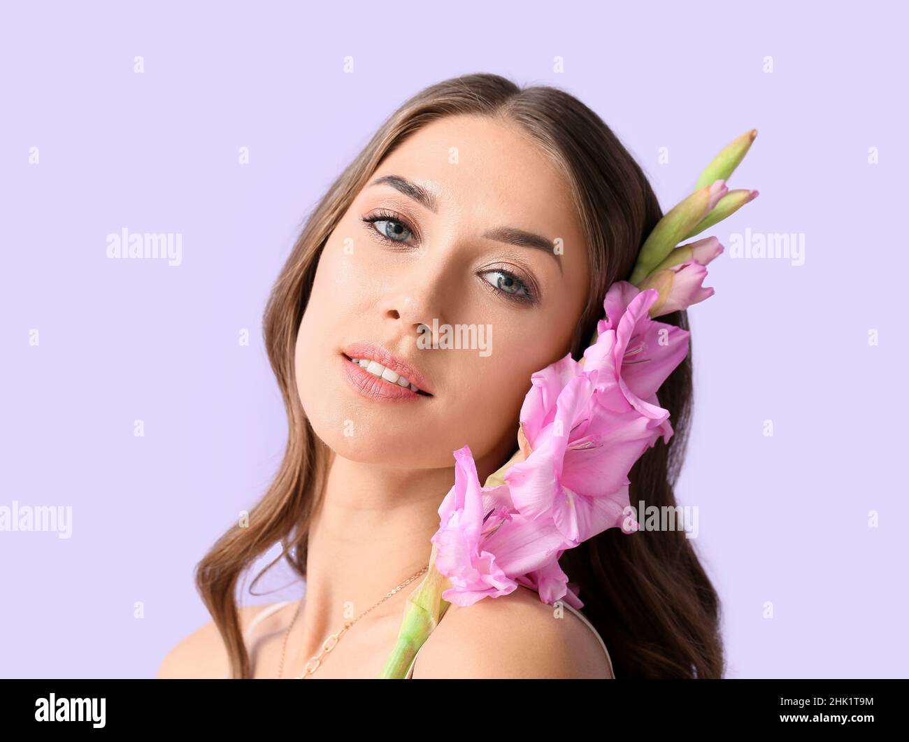 Young woman with Gladiolus flowers on color background Stock Photo