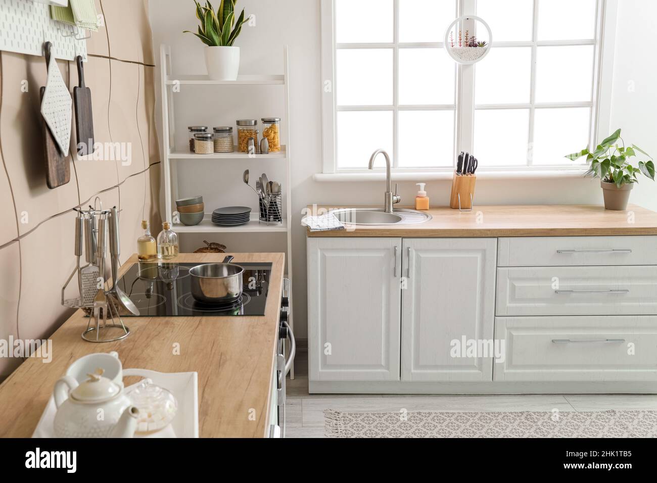 Interior of light kitchen with white counters, silver sink and shelving ...