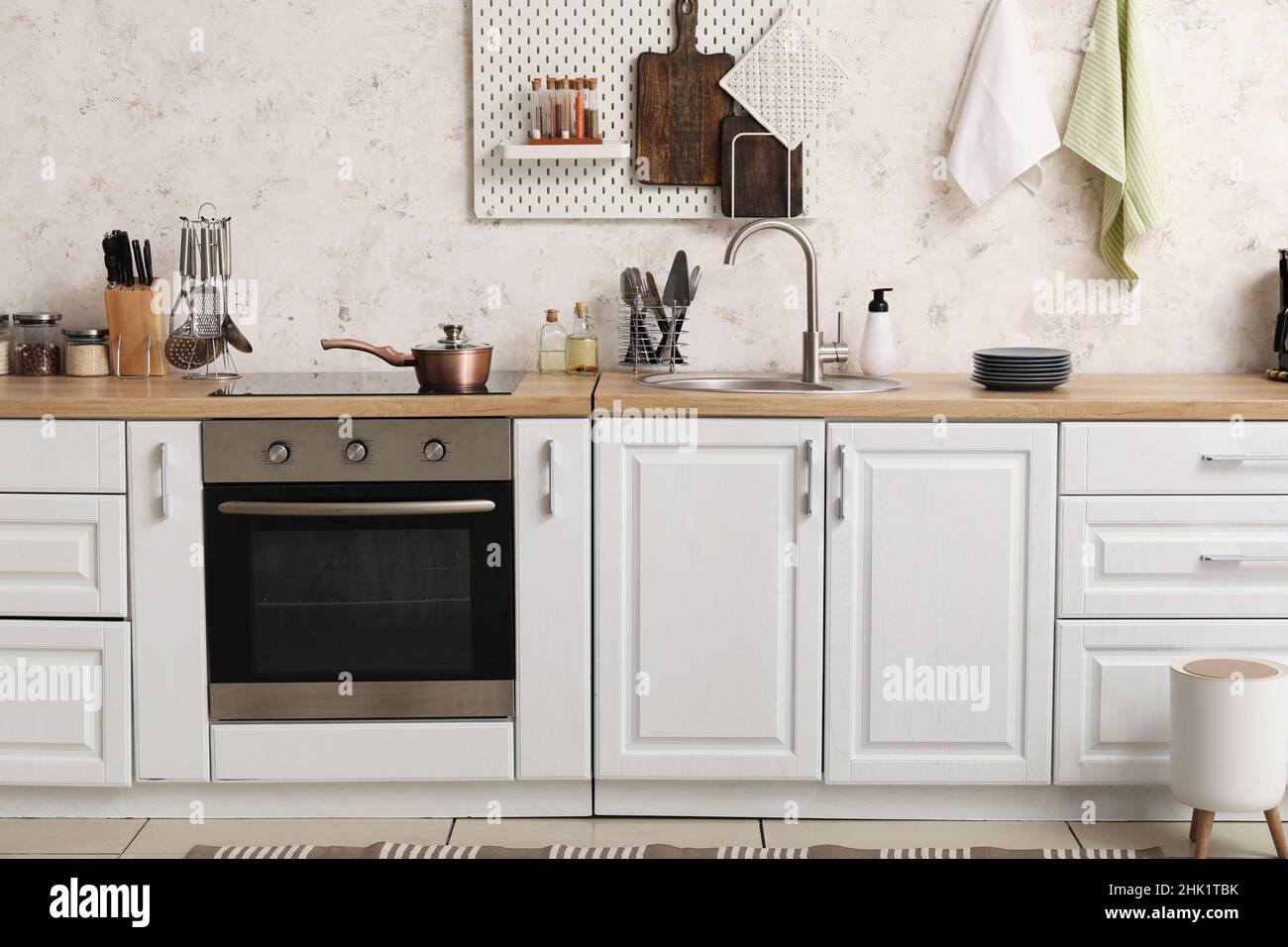 Interior of modern kitchen with white counters, silver sink and oven ...