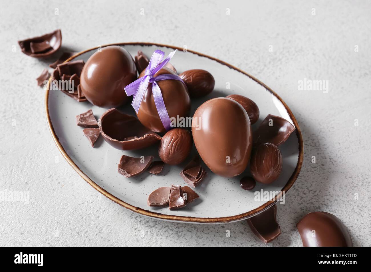 Plate with chocolate Easter eggs on light background Stock Photo