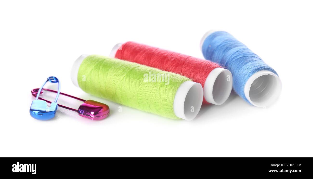 Multicolored thread spools and safety pins on white background Stock Photo
