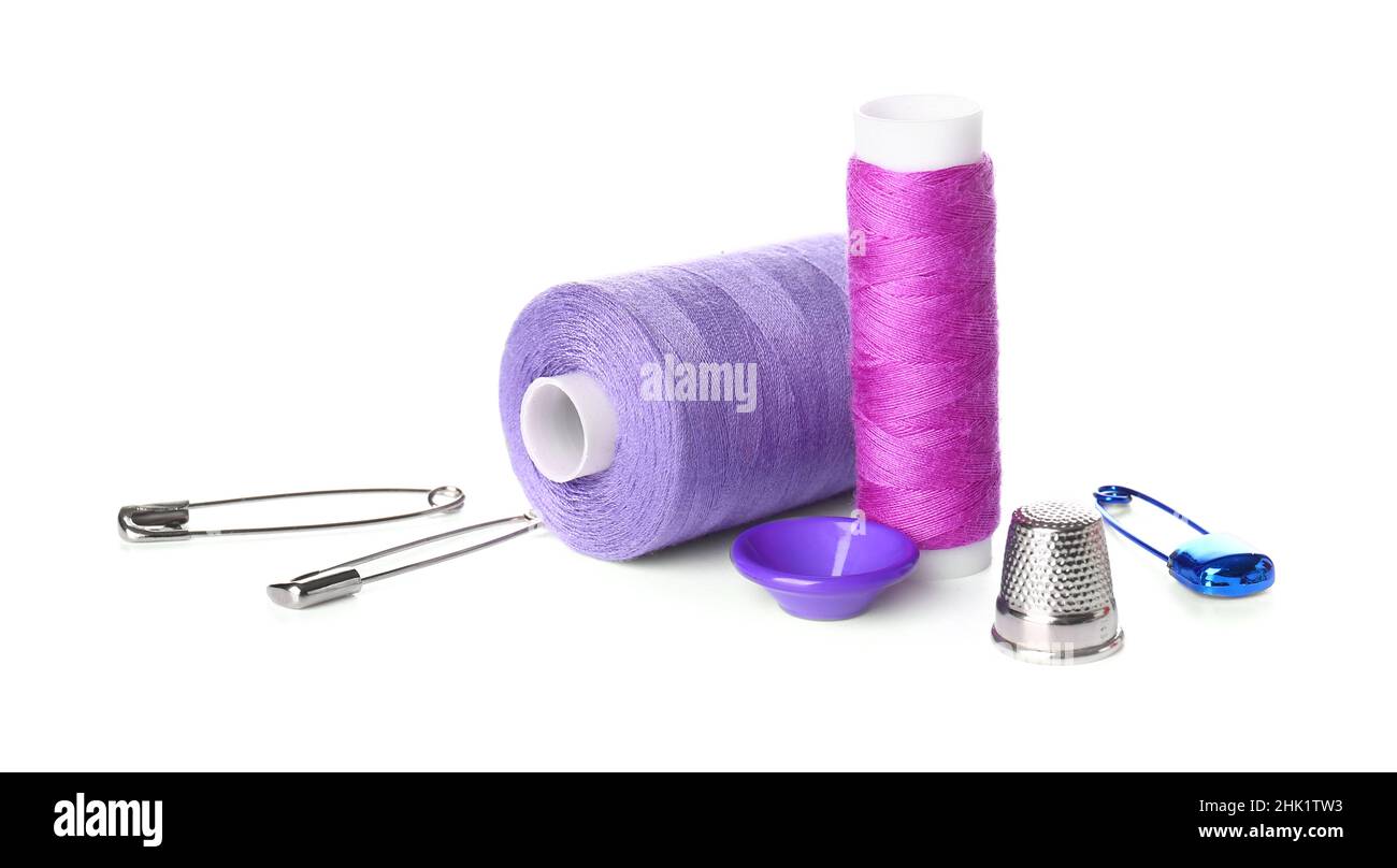 Thread spools, button, thimble and safety pins on white background Stock Photo
