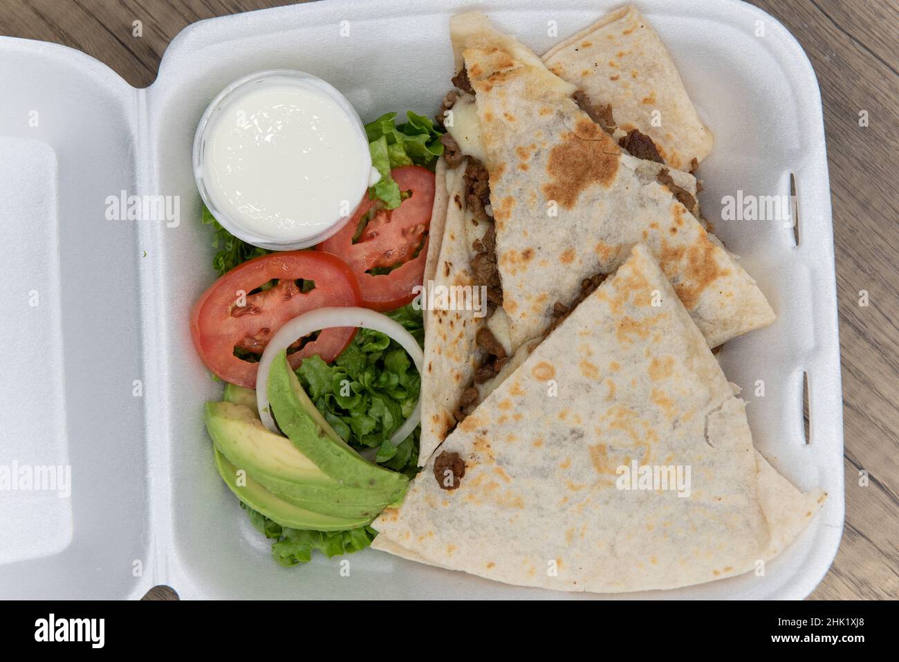 Overhead view of take out order of carne asada tortilla quesadillas cut into triangle pieces and served in styrofoam box. Stock Photo