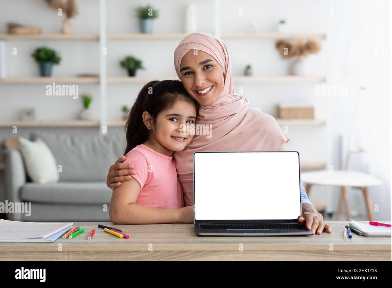 Muslim Woman And Her Little Daughter Demonstrating Laptop With Blank ...
