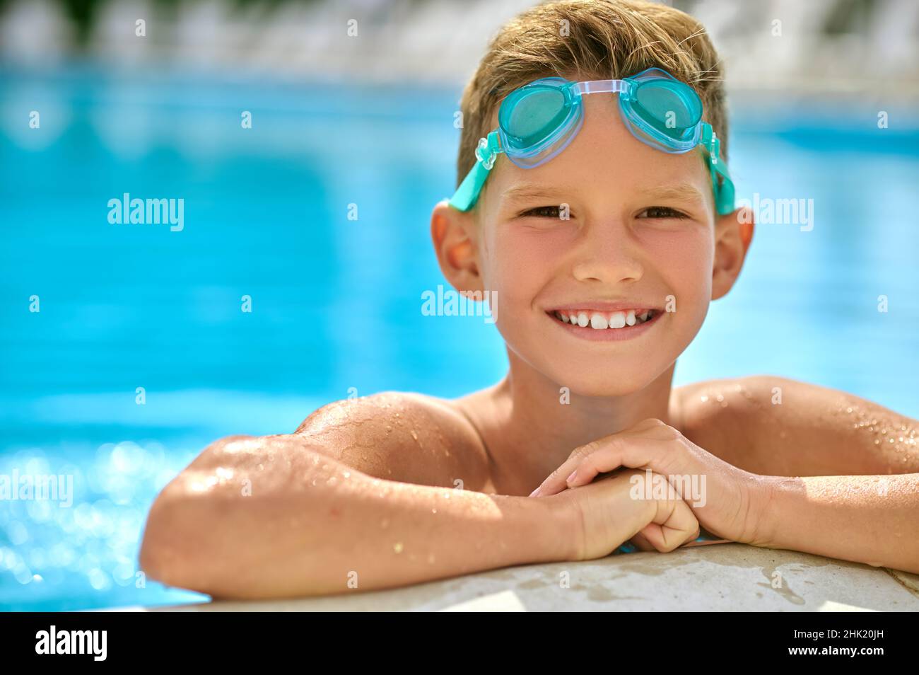 Boy with goggles smiling at camera in pool Stock Photo Alamy