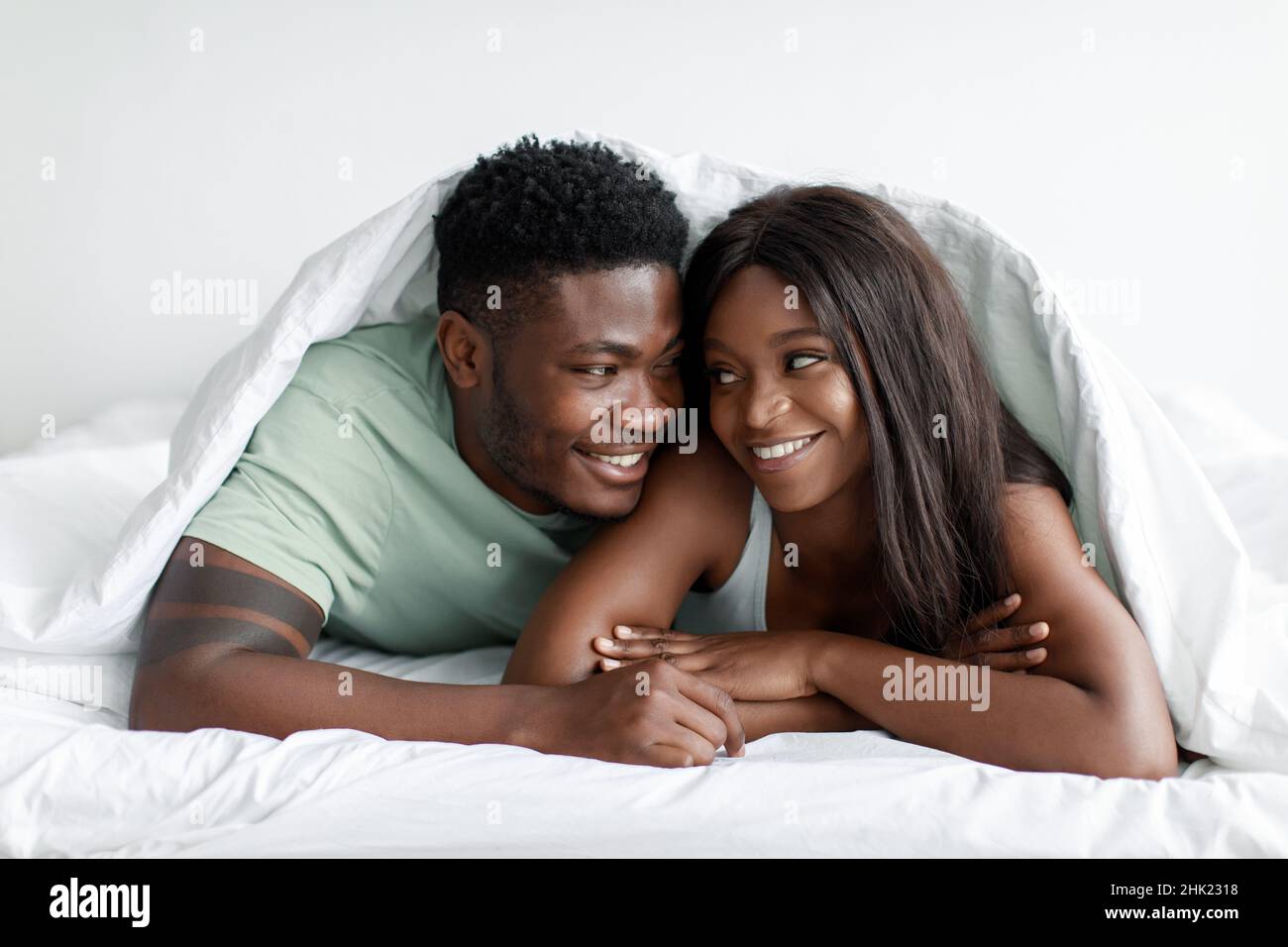 Portrait of smiling glad millennial african american husband and wife wake up enjoy tender moment Stock Photo