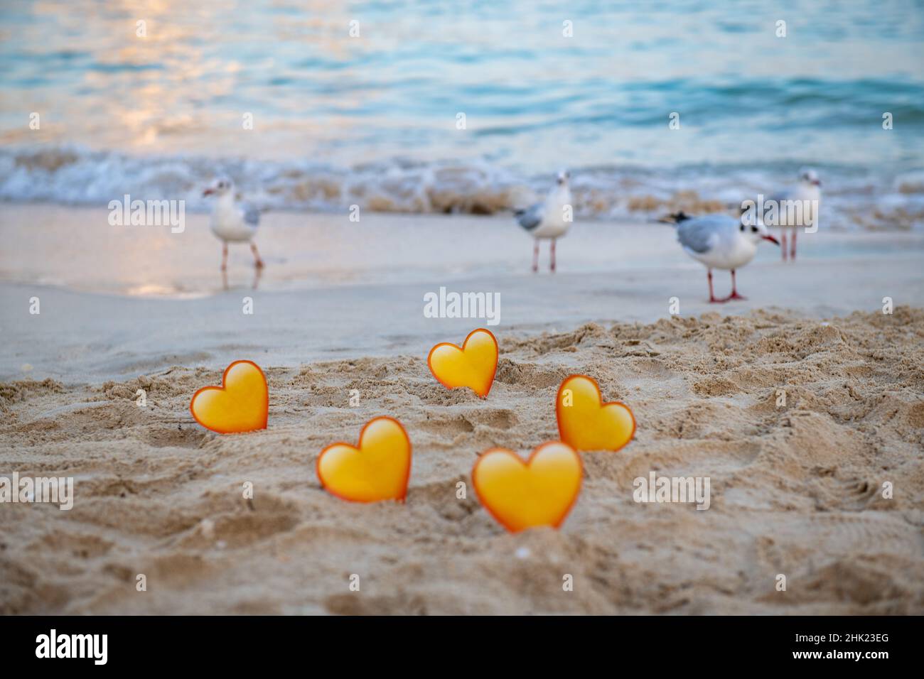 birds and yellow hearts in the sand stand on the sea Stock Photo