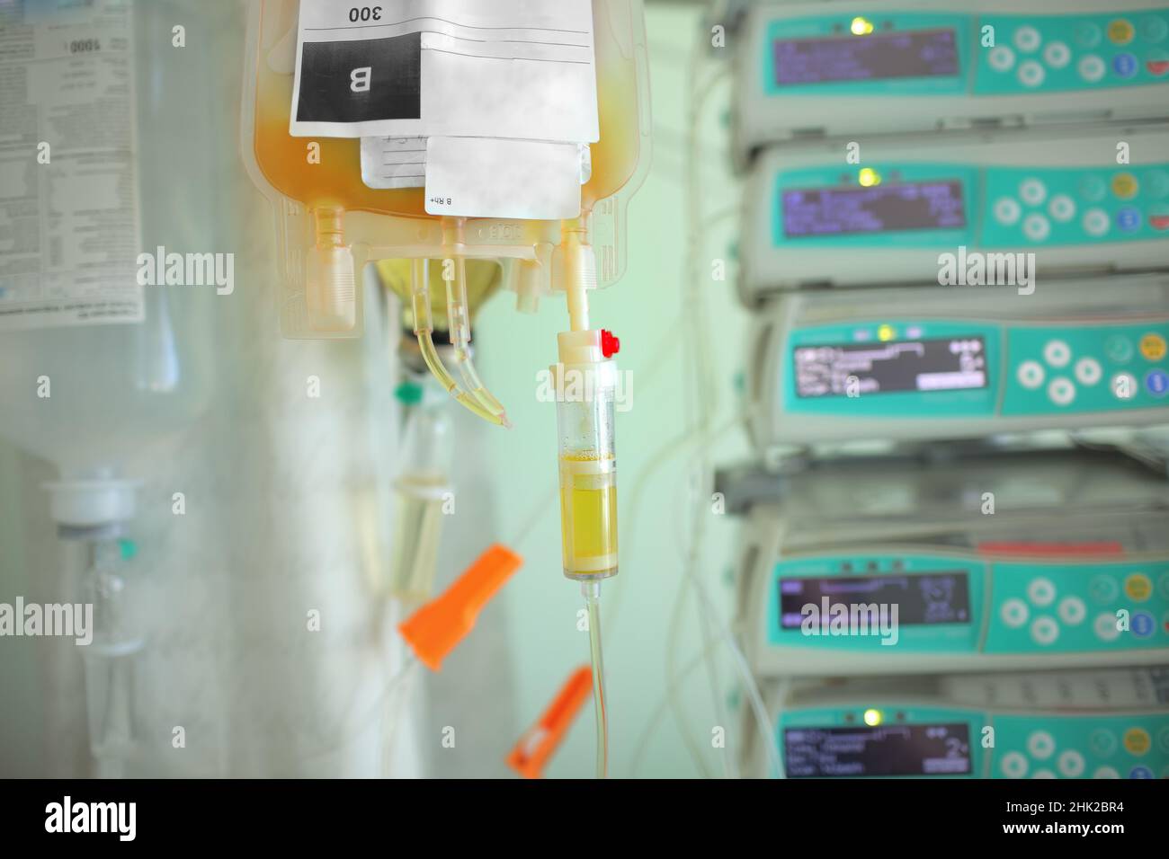 Blood plasma bag dripping to the patient on the background og medical equipment. Stock Photo