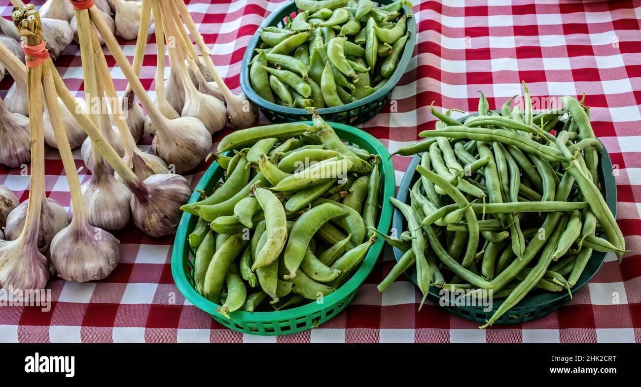 Garlic, green peas, and green beans for sale at a farmer's market in the summer. Stock Photo