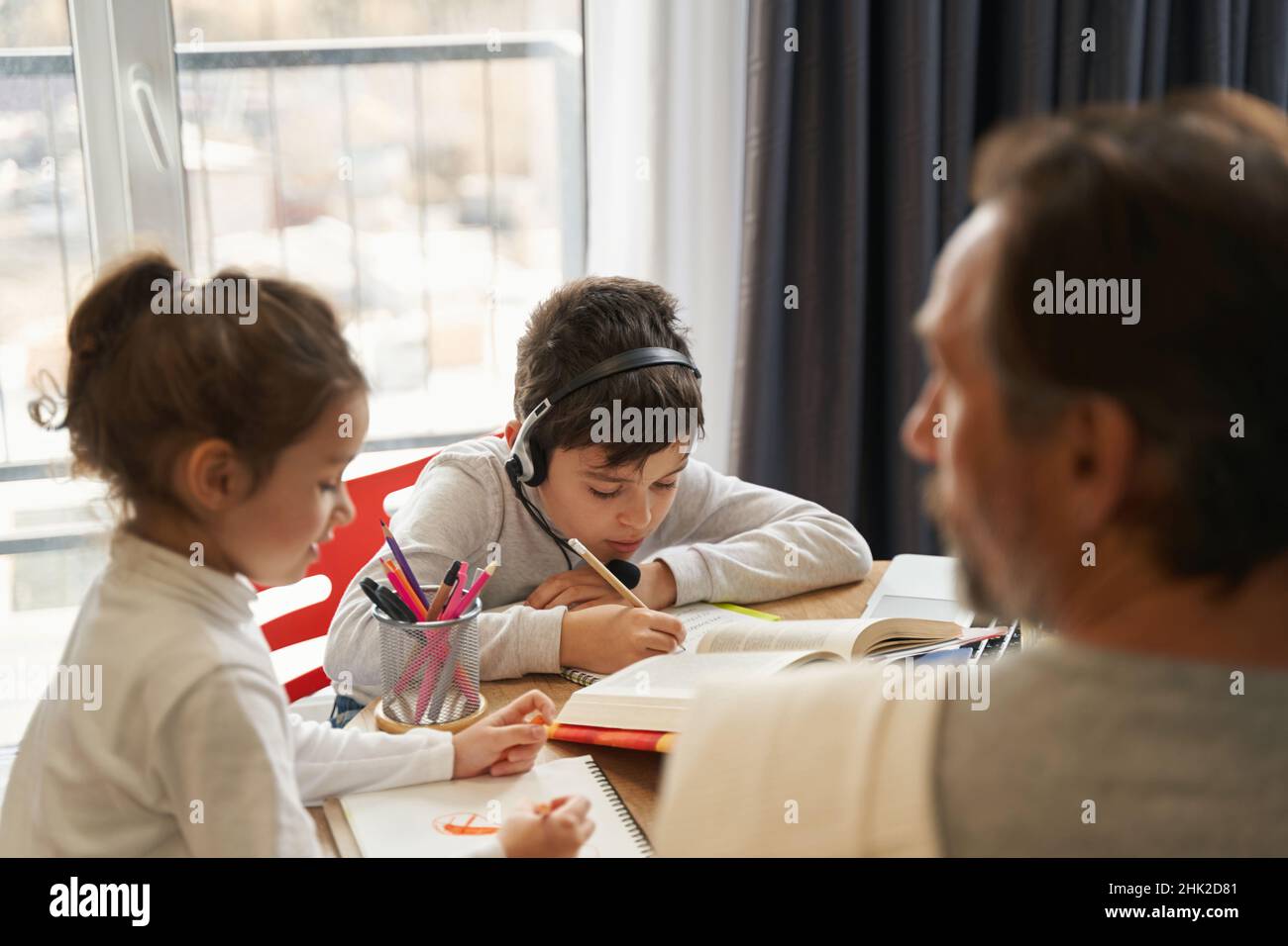 Boy in headset doing homework in the kitchen Stock Photo