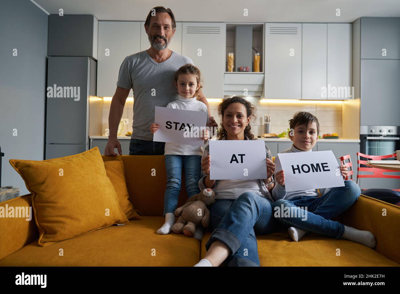 Smiling family holding signs with warning to stay at home Stock Photo