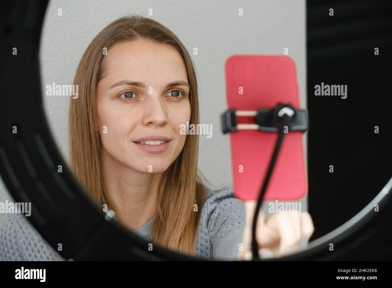 Woman looking at the smartphone camera with ring light. Blogger streaming in social media channel blogger recording vlog on digital smartphone cam Stock Photo
