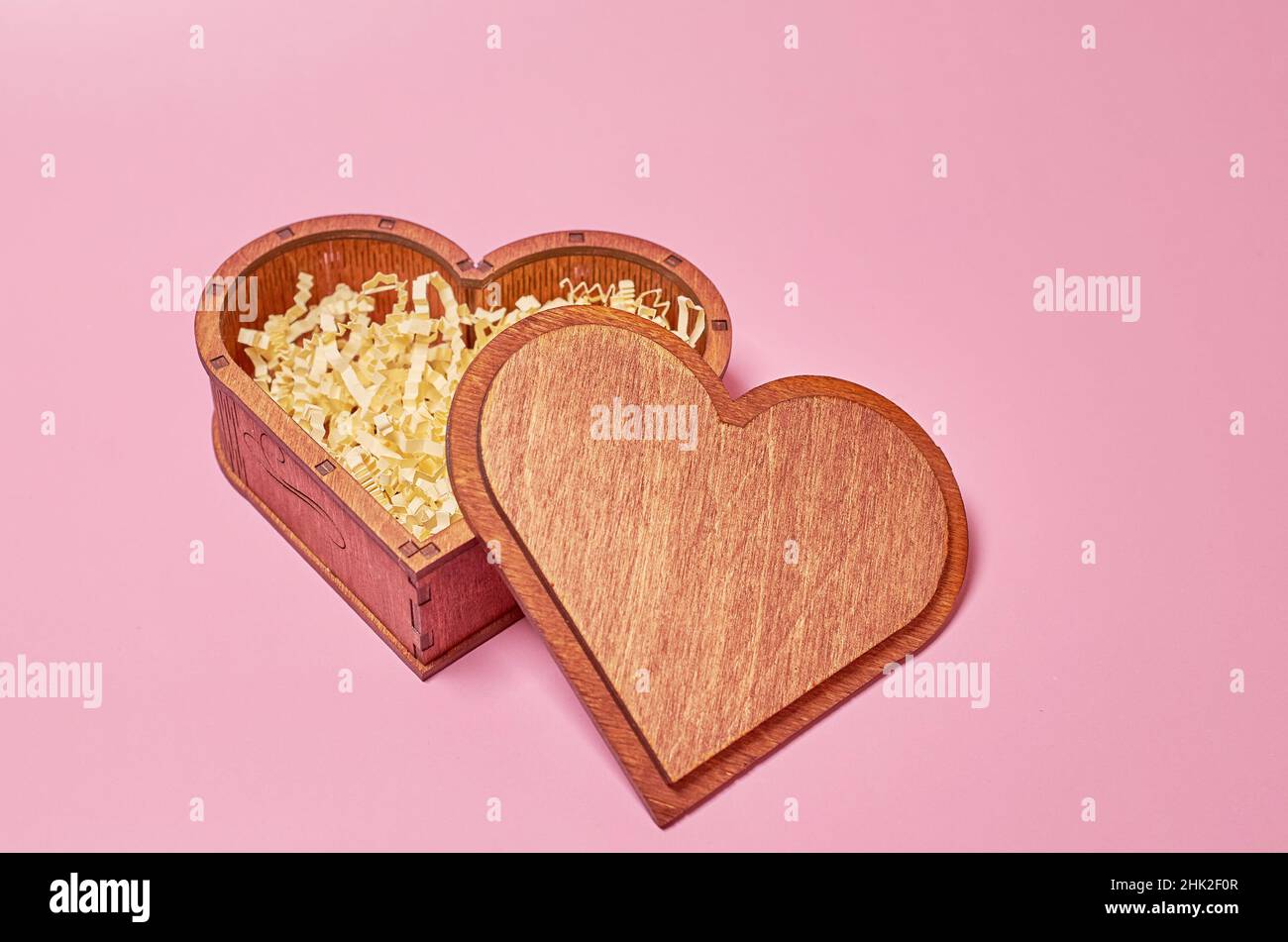 Wooden gift box in the shape of a heart with paper filling with an open