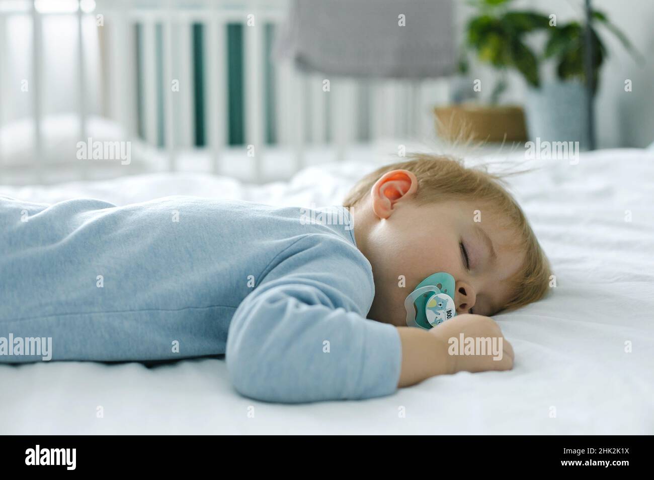 2 years old boy child relaxing in bed in light scandinavian bedroom in