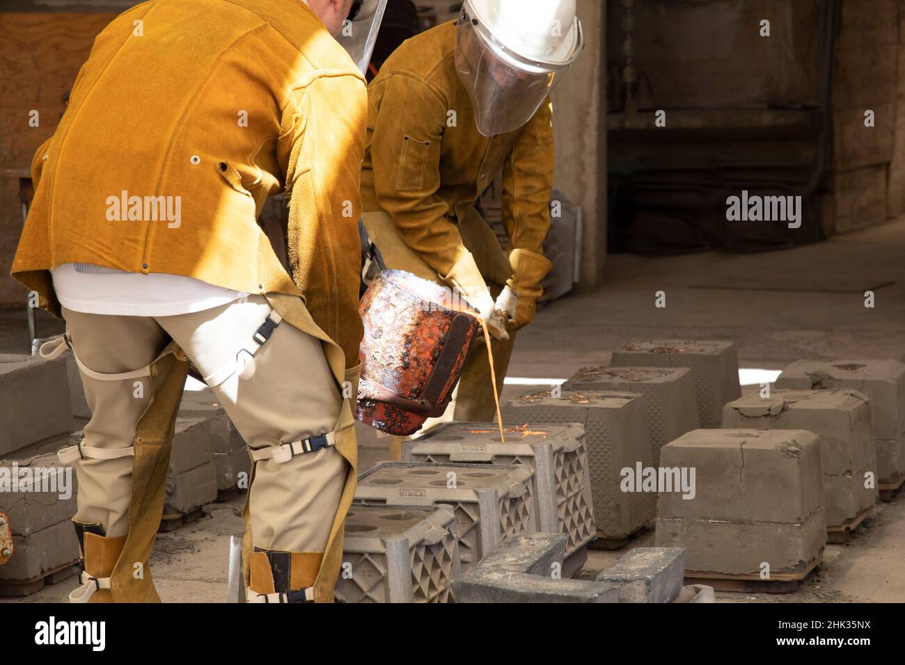 USA, Arizona, Scottsdale. Windbell casters pouring molten bronze into bell molds. Stock Photo
