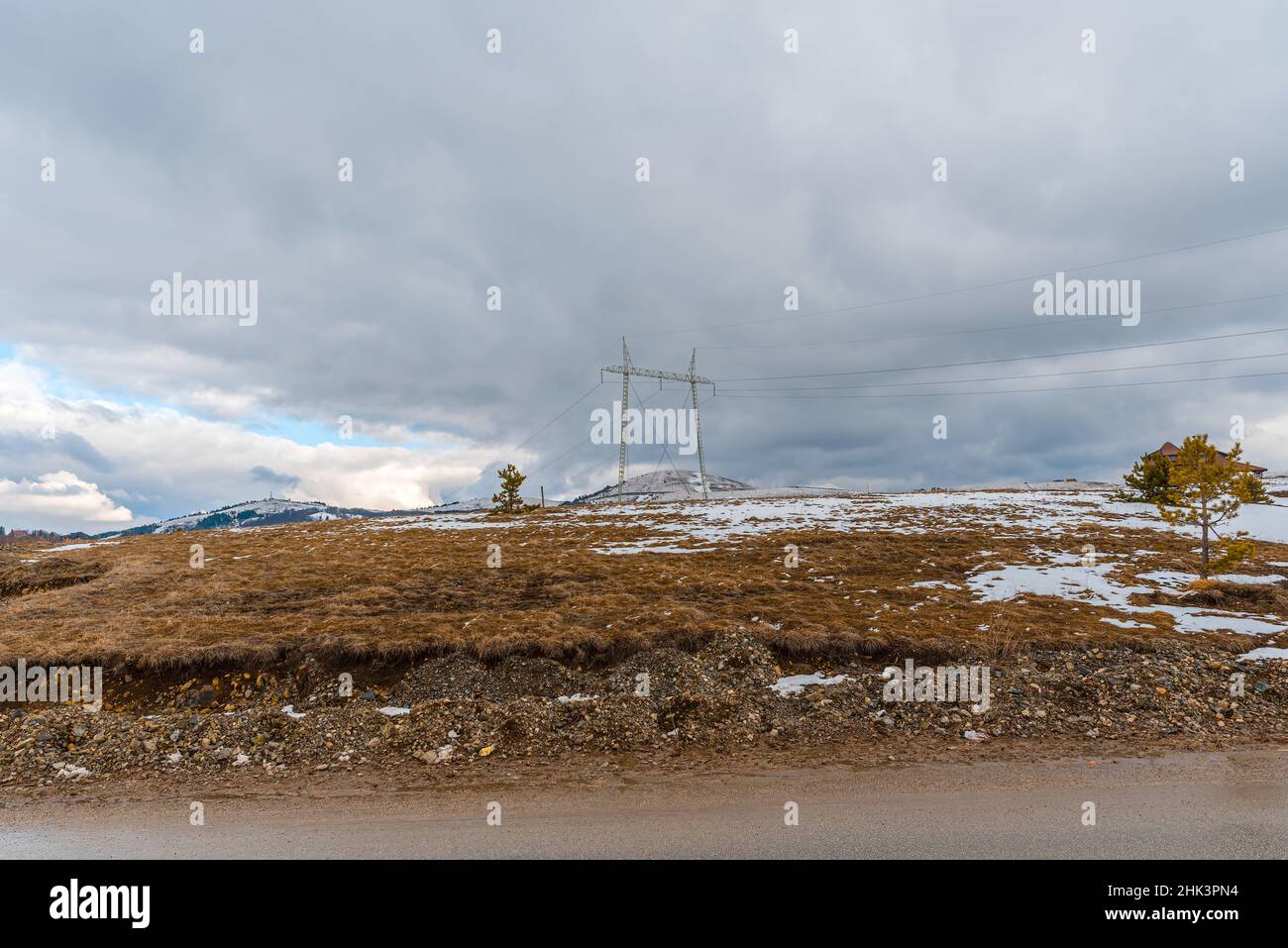 High voltage power line in the mountains with snow on mountains and dry ...