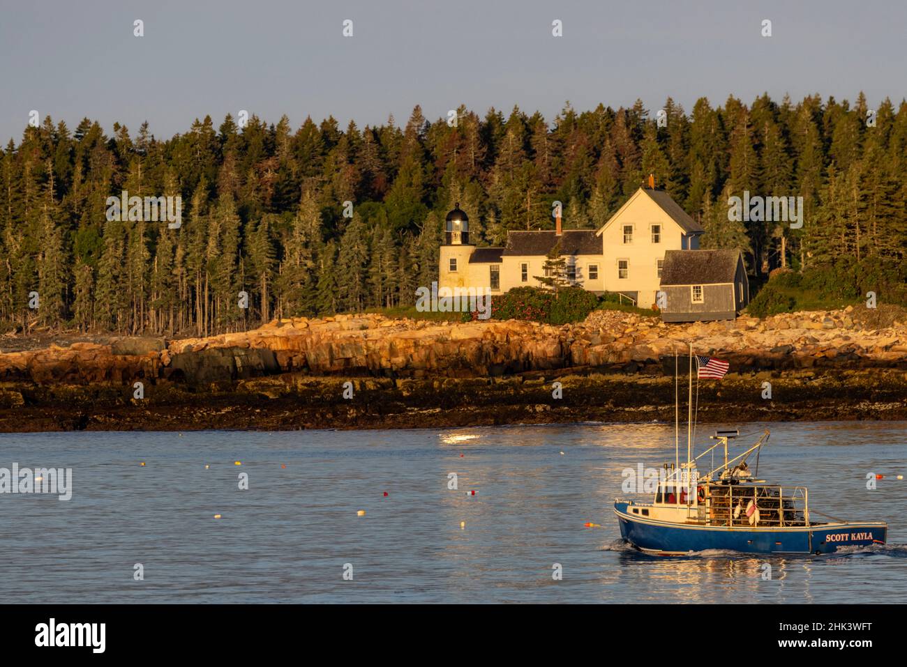 Lobster boats checking traps with lighthouse in background in Winter