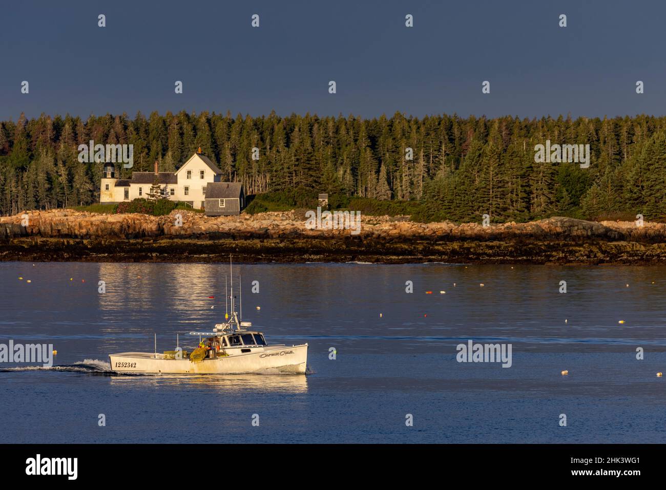 Lobster boats checking traps with lighthouse in background in Winter