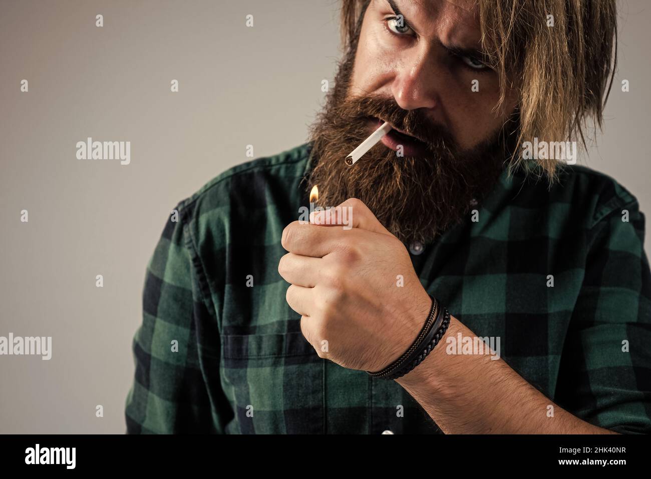 smoke a cigarette. bearded man. mature hipster with beard use a lighter. brutal caucasian hipster with moustache smoking cigarette. male bad habit Stock Photo