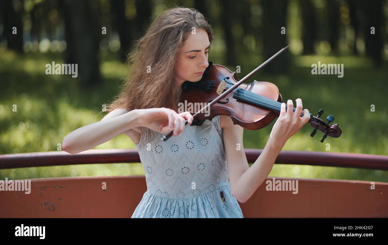 A young girl plays the violin in the city park Stock Photo - Alamy