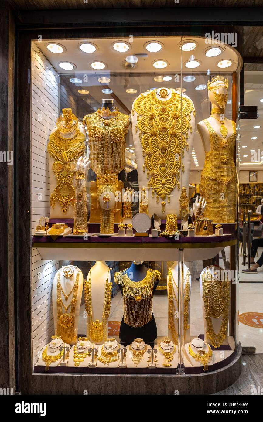 Golden jewellery - massive golden necklaces, armors, rings and hats displayed in a gold store in Dubai Gold Souk, Deira. Stock Photo
