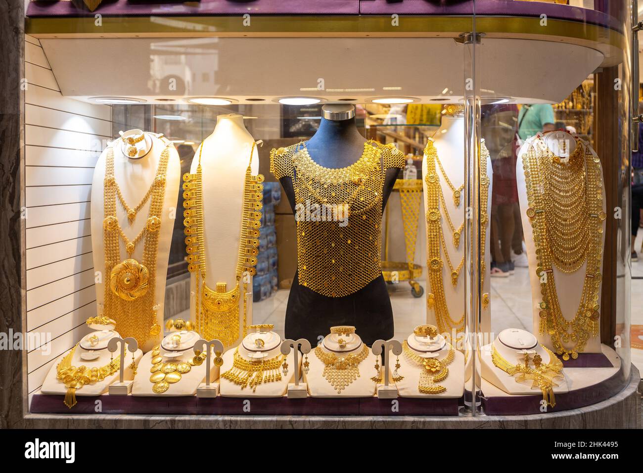 Dubai Gold Souk - golden jewelry - massive golden necklaces, armors, rings and hats displayed in a gold store. Stock Photo