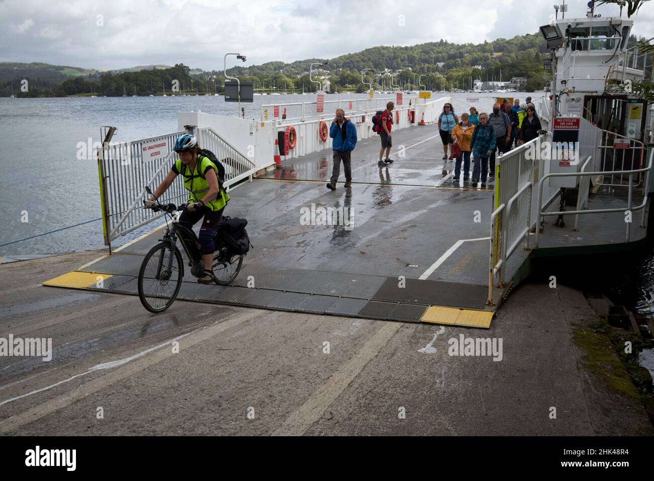 cyclist disembarking windermere ferry terminal at far sawrey looking across to bowness-on-windermere lake district, cumbria, england, uk Stock Photo