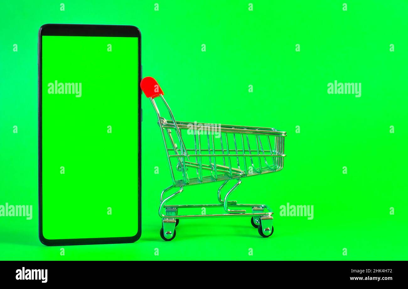 concept of delivery, online food shopping. metal empty grocery cart cart on green background. Stock Photo