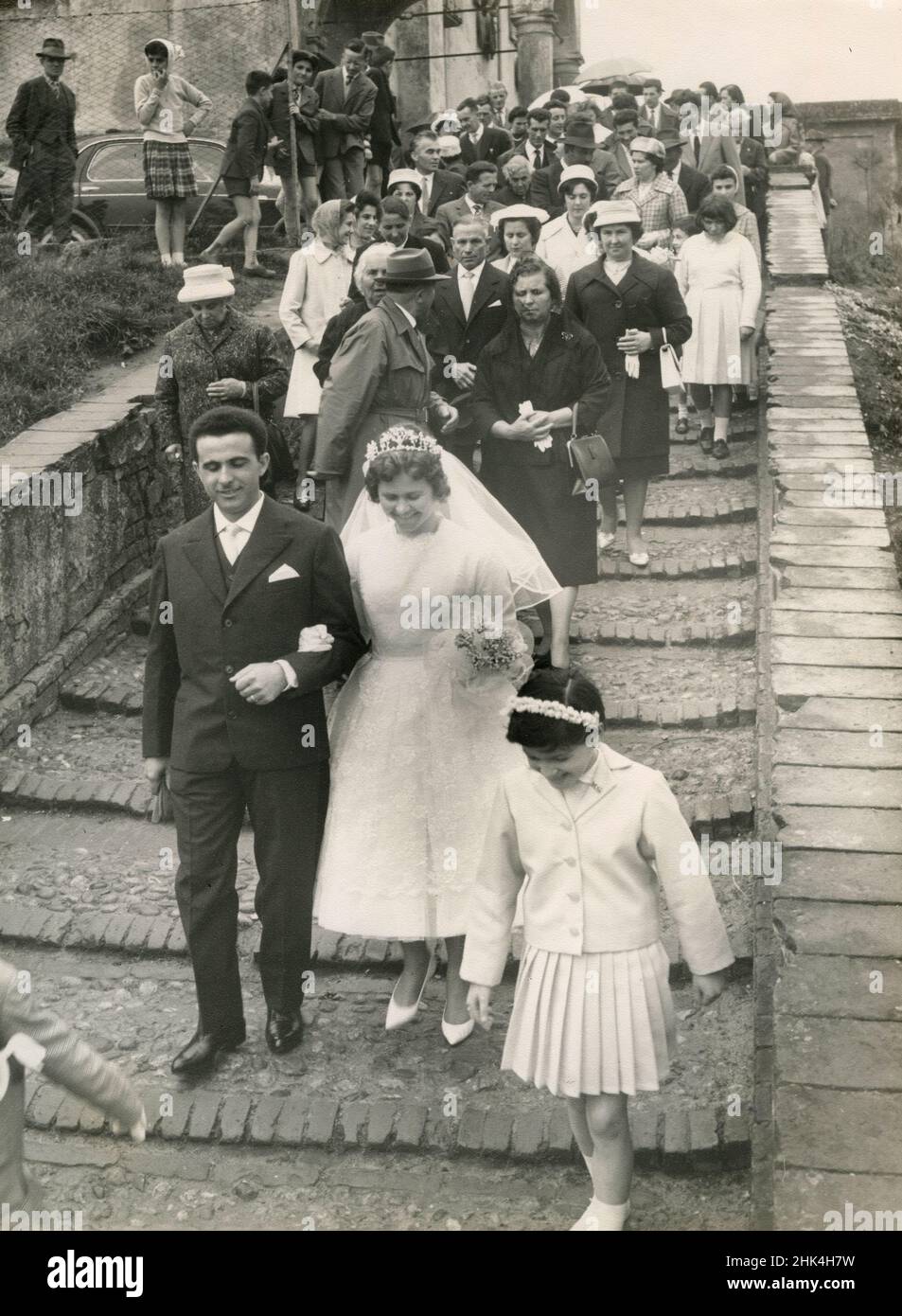 Wedding in Italy during the 1950s: The bride and the groom just married go out of the church with the children followed by all the guests Stock Photo