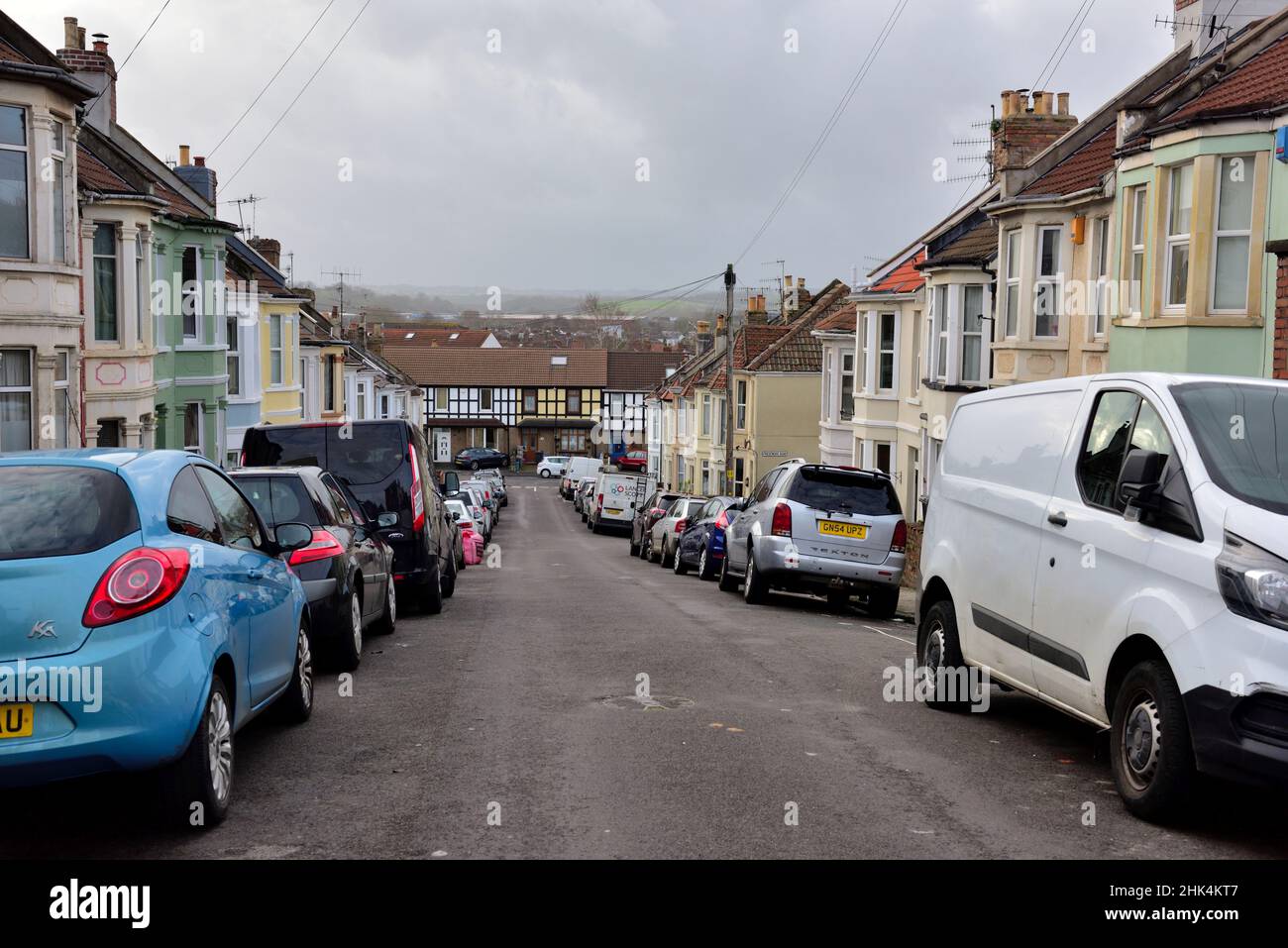 Small residential street in city with cars and vans parked on both sides of the road, Bristol, UK Stock Photo