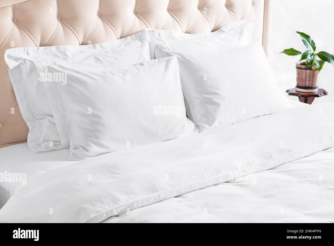 Bedroom with bed, white bedding, and bedside table. White pillows