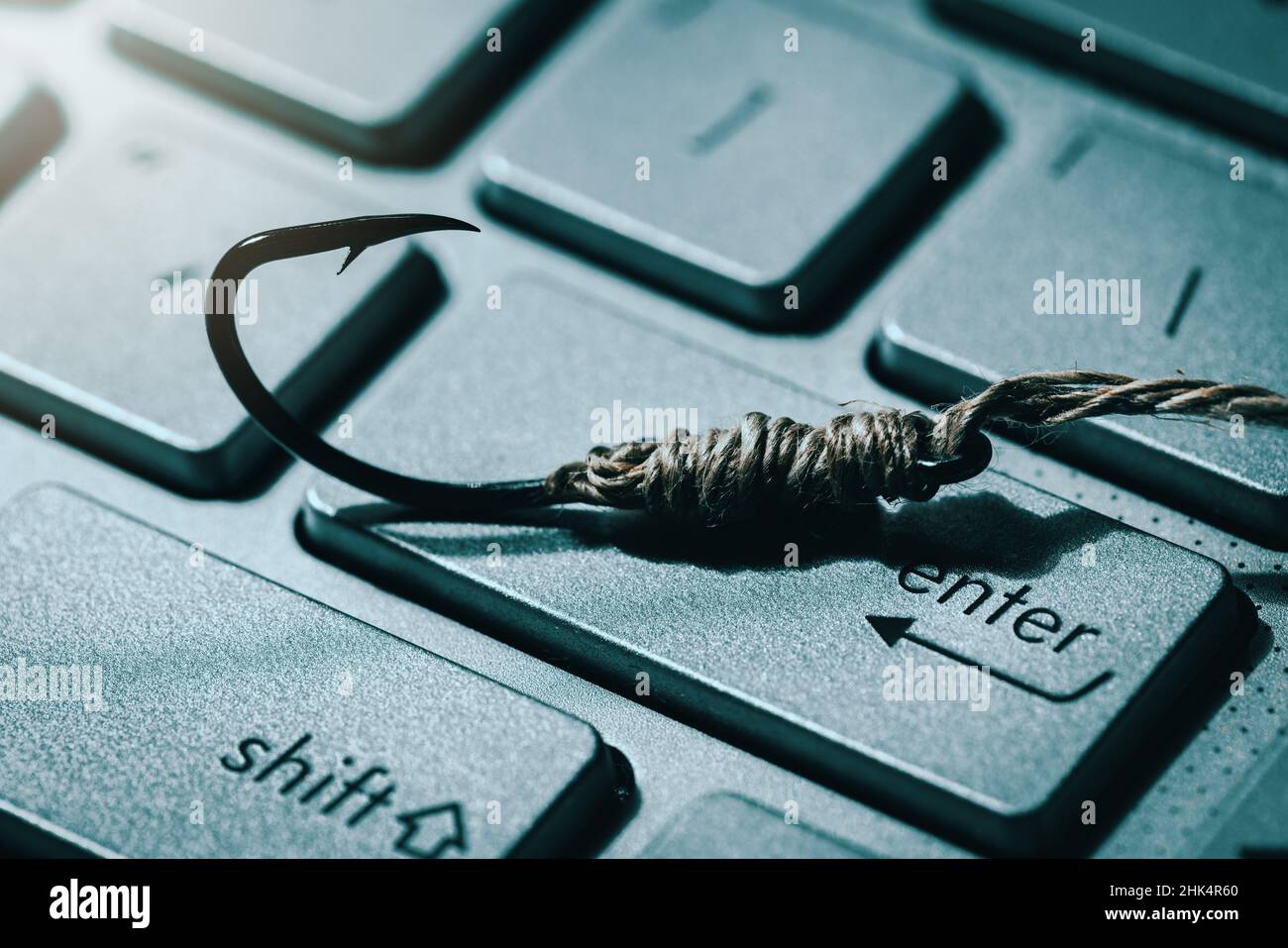 phishing and cyber crime concept. fishing hook on computer keyboard Stock Photo