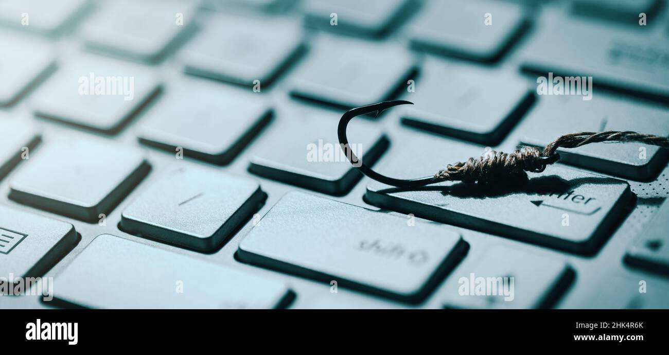 phishing and cyber crime concept. fishing hook on computer keyboard. copy space Stock Photo