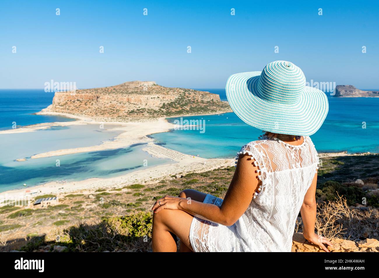 Portrait of woman with hat admiring the idyllic beach and lagoon sitting on top of hill, Balos, Crete, Greek Islands, Greece, Europe Stock Photo