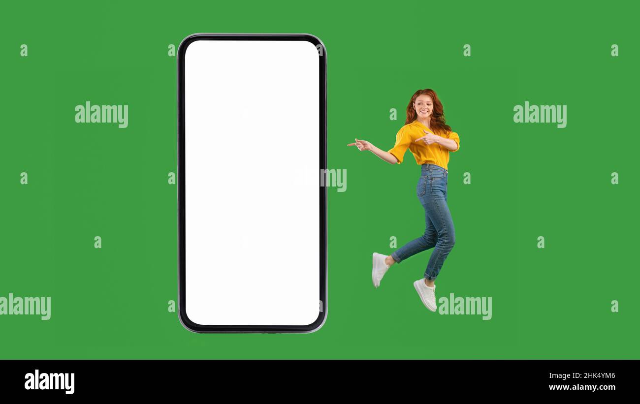 Young Lady Pointing At Blank Smartphone Screen Jumping, Green