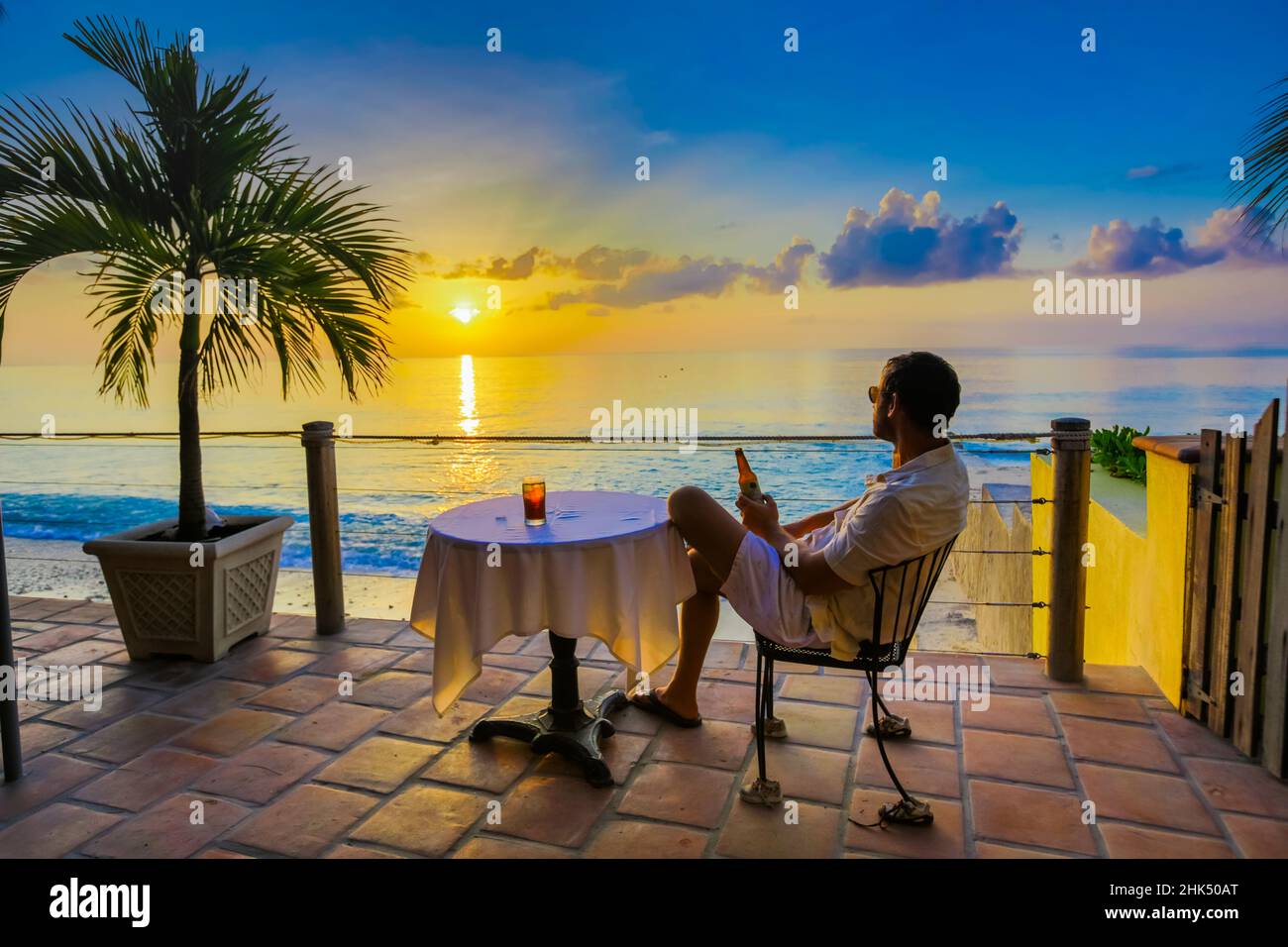 Man enjoying a beverage on a patio at sunset in Turks and Caicos Islands, Atlantic, Central America Stock Photo