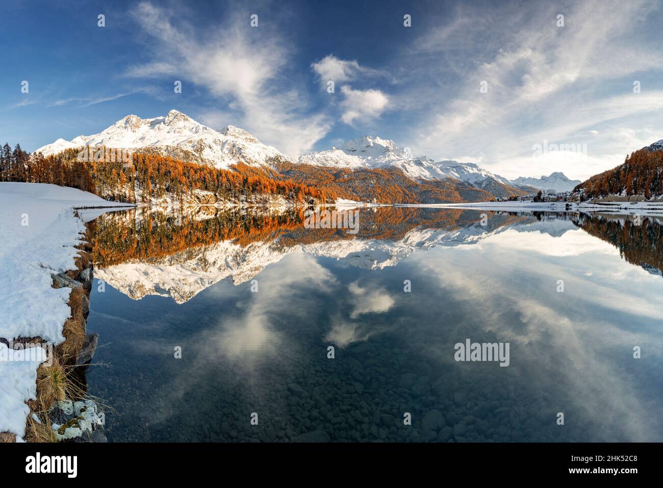 Autumn woods and snowcapped mountains mirrored in the clear water of Champfer lake at sunset, Engadine, Graubunden, Switzerland, Europe Stock Photo