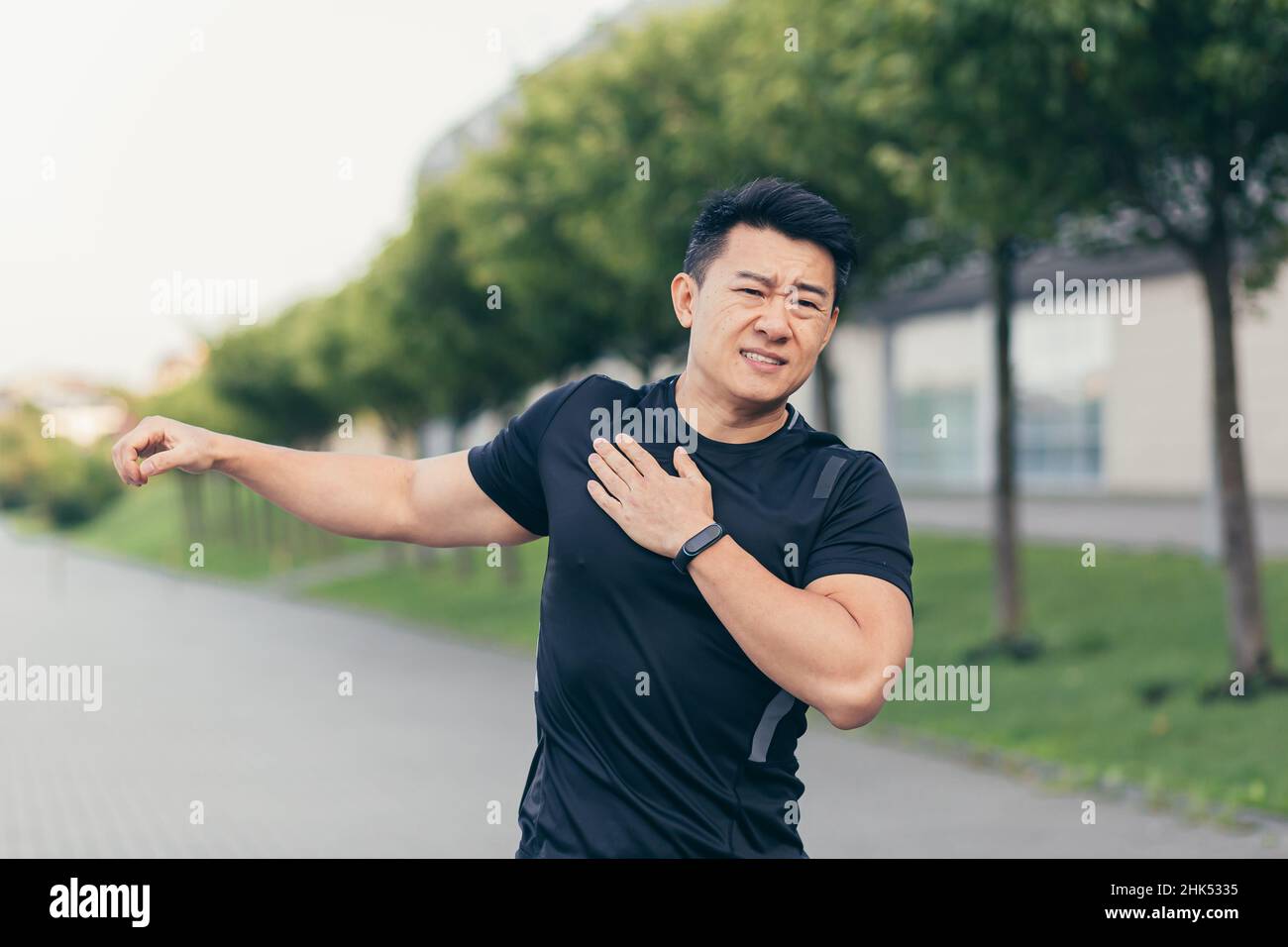 Male asian athlete, kneading shoulder pain, sore arm muscles in the ...