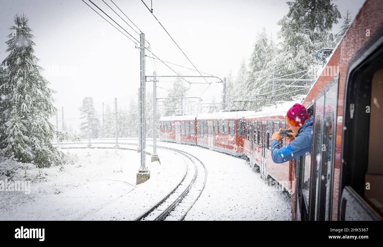 Man photographing the snow falling over mountains during a trip on board of Gornergrat Bahn train, Zermatt, Valais, Switzerland, Europe Stock Photo