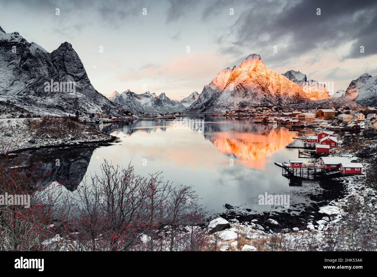 Clouds at dawn over traditional Rorbu and Olstind mountain reflected in sea, Reine Bay, Nordland, Lofoten Islands, Norway, Scandinavia, Europe Stock Photo