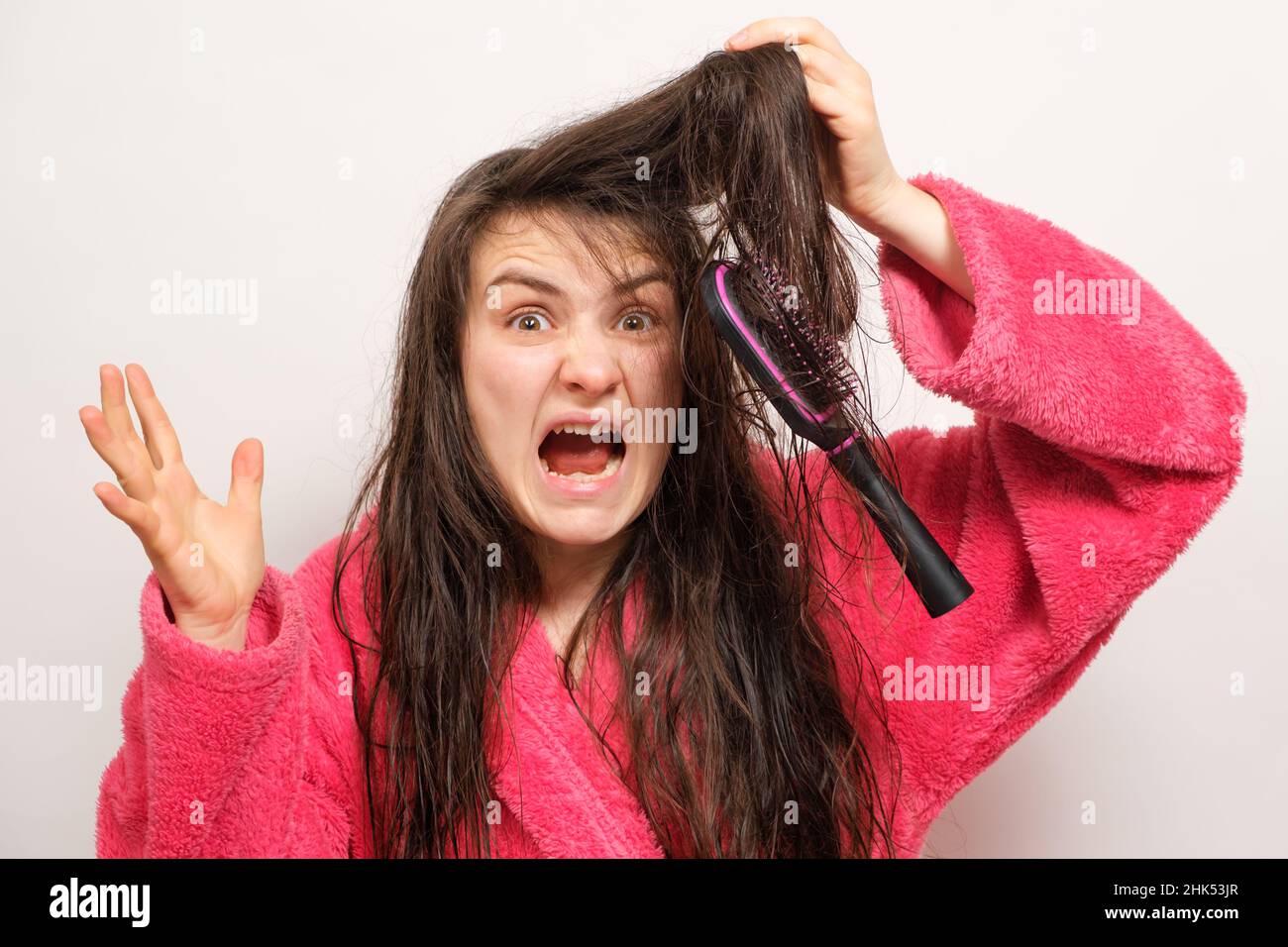 A woman with wet long tangled hair tries to comb Stock Photo