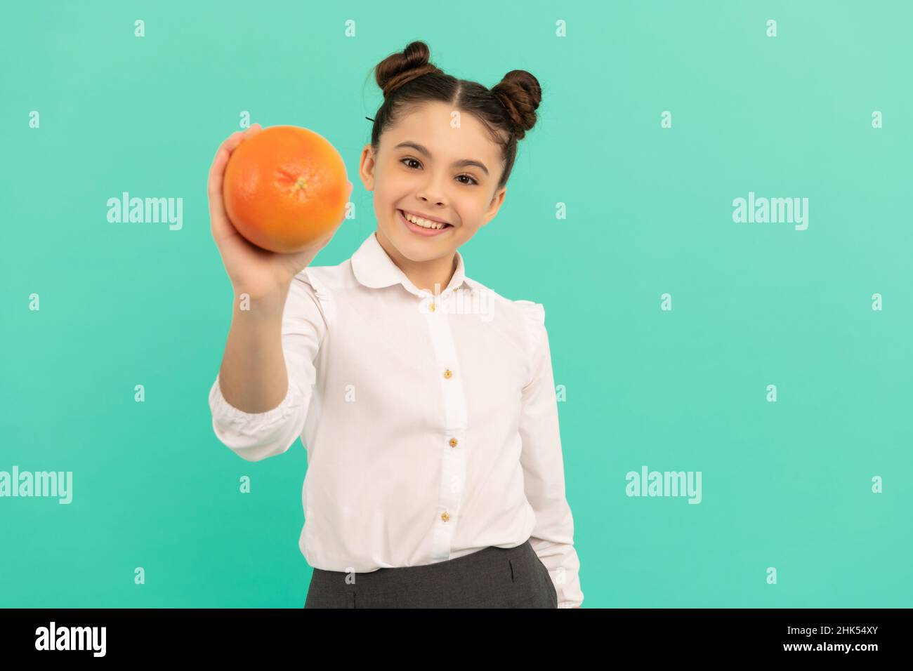 smiling school kid with grapefruit on blue background, dieting Stock Photo